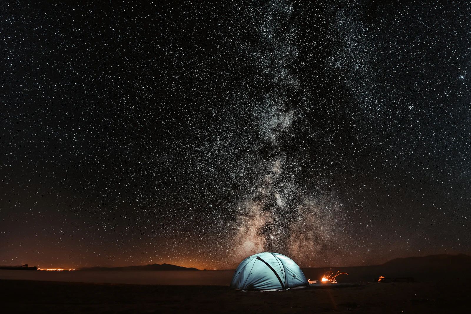 Illuminated tent under the Milky Way during night testing