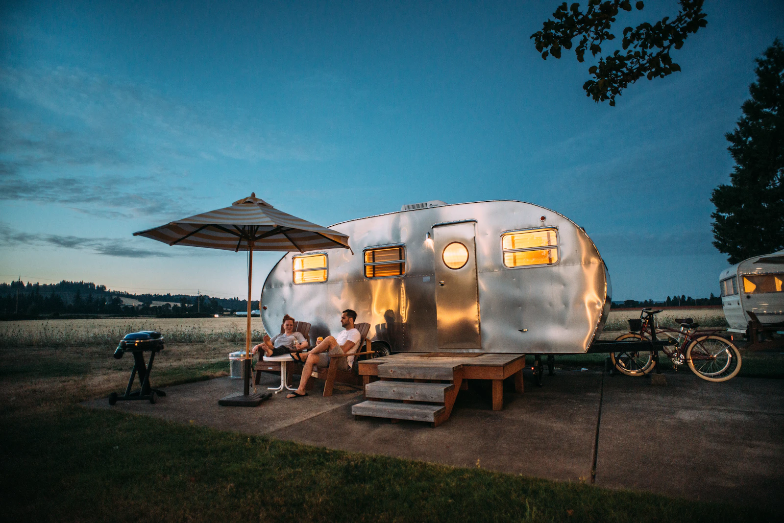 Campsite with a lit camper trailer at dusk