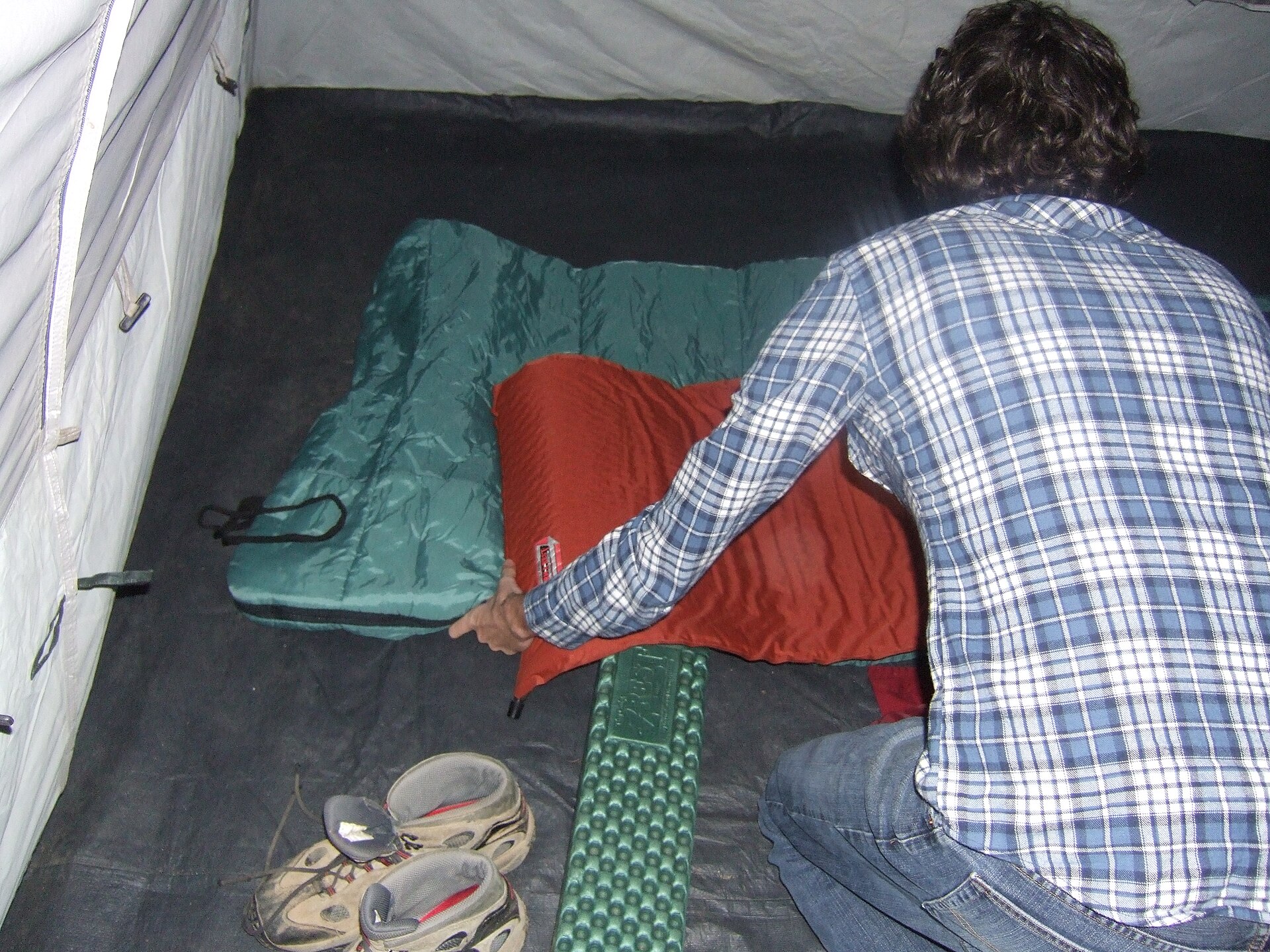 A sleeping bag laid out inside a tent with morning light coming through
